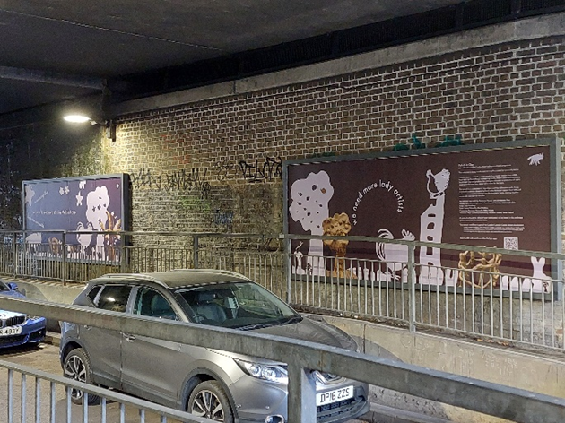 2 pieces of artwork on an underpass and some cars driving past